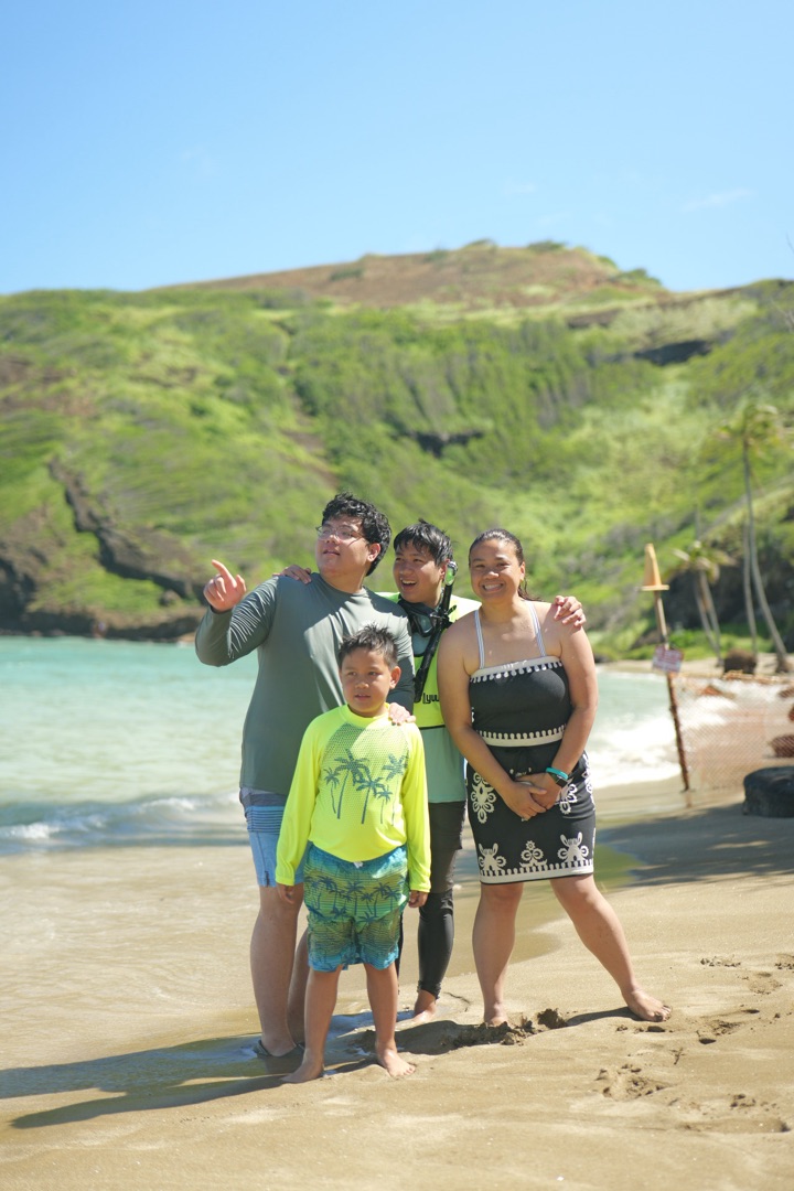 Family posing at Hanauma Bay beach with snorkel gear