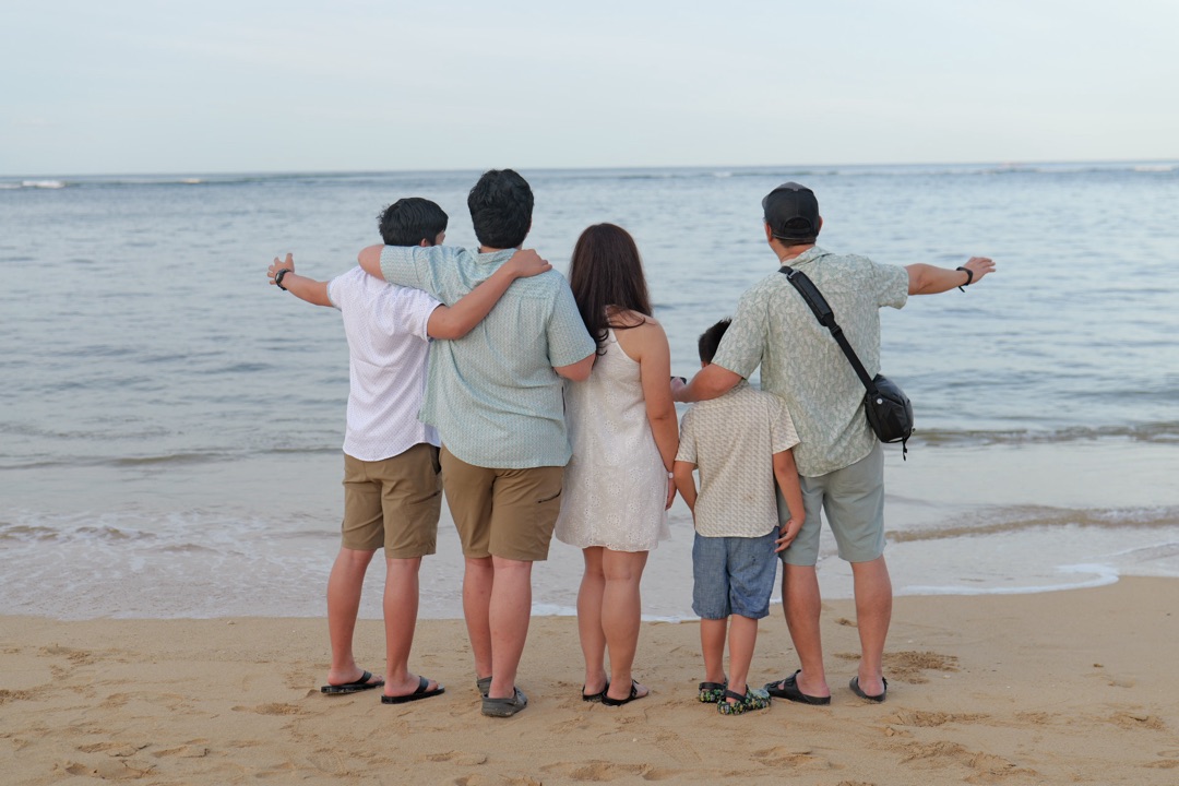 Family watching the sunset together on Waikiki Beach